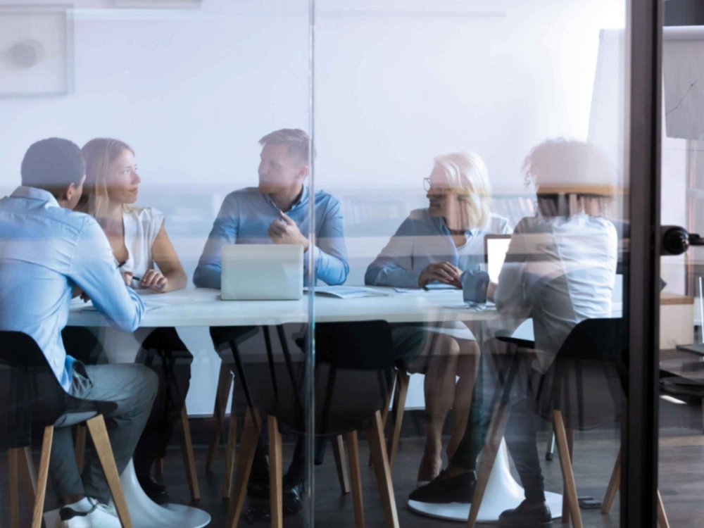 Personen sitzen in einem Besprechungsraum und halten ein Meeting ab