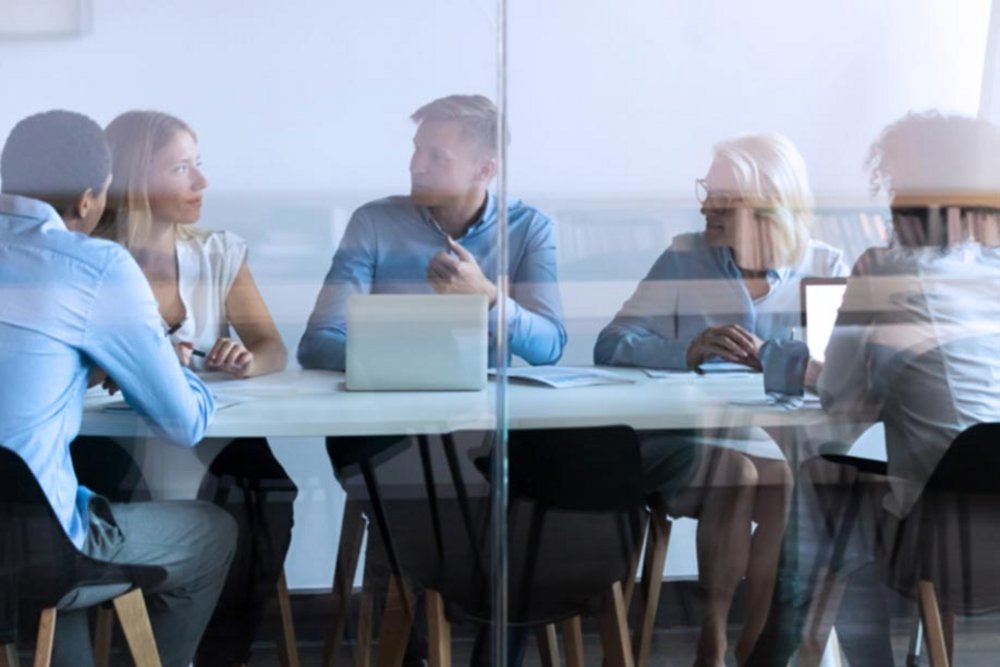 Personen sitzen in einem Besprechungsraum und halten ein Meeting ab