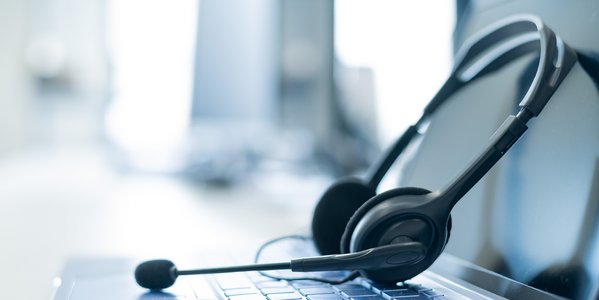 Aufgeklappter Laptop und ein Headset.