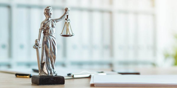 Nahaufnahme von einer Justitia-Figur auf einem Schreibtisch.