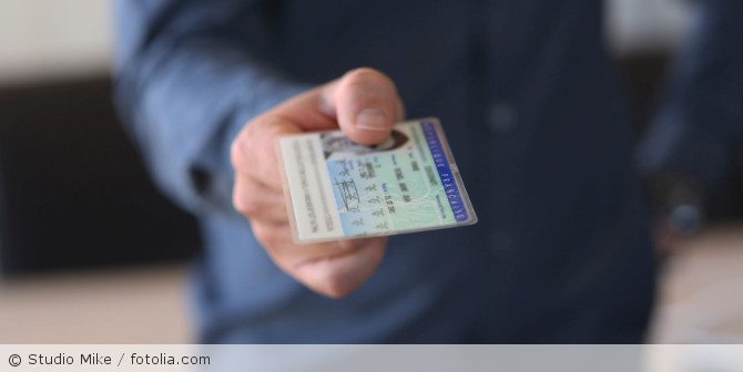 Eine Person die ihren Ausweis in der Hand hält.