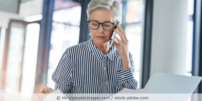 Businessfrau am Schreibtisch mit Telefon und Laptop