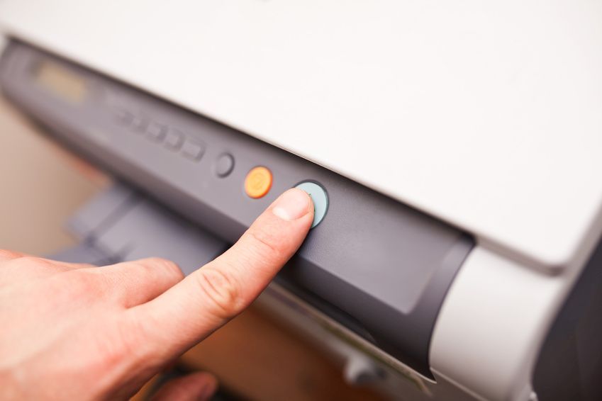 Mann drückt auf ein grünen Knopf am Drucker.