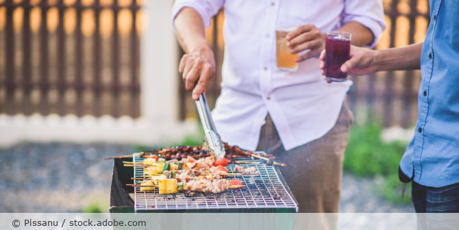 Männer die am Grill stehen.