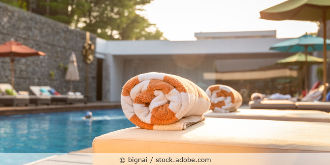Liegen mit Handtüchern stehen an einem Pool.