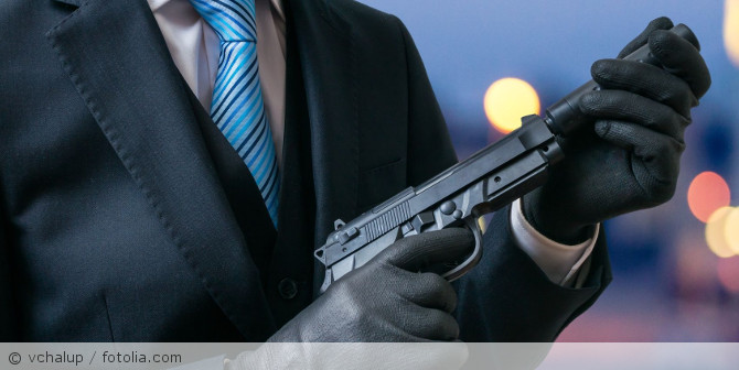 Ein Mann im Anzug mit einer Waffe in der Hand.