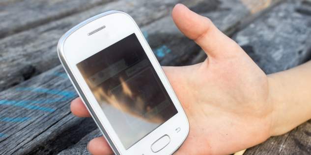 Kind hält sein weißes Smartphone in der Hand.