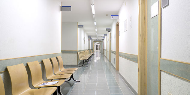 Leeres Krankenhaus mit belichtetem Gang und leeren Stühlen.