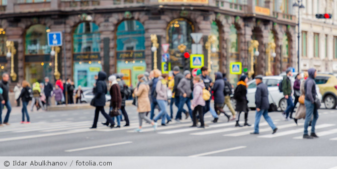 Mehrere Menschen überqueren eine Straße in einer Stadt.