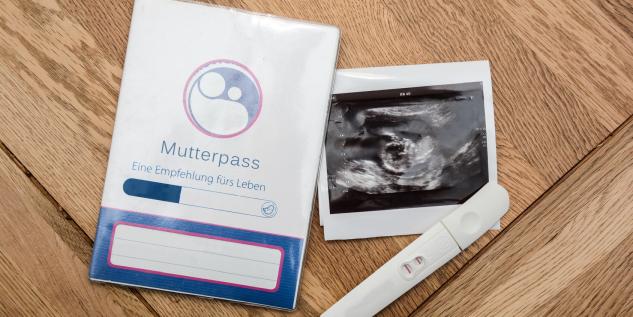 Ein Mutterpass, ein positiver Schwangerschaftstest und ein Ultraschalbild.