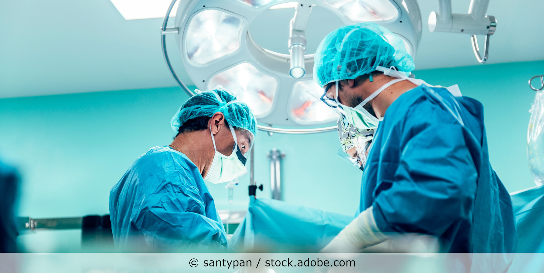 Drei Ärzte stehen an einem Operationstisch im Krankenhaus und operieren einen Patienten.
