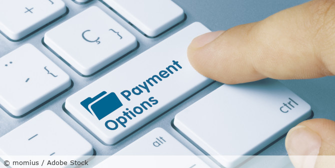 Eine Computertastatur mit der Aufschrift "Payment Options" auf einer Taste, über der ein Finger schwebt.