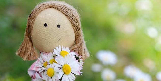 Eine Puppe mit zwei Zöpfen, die Blumen in der Hand hält.