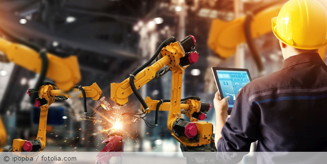Ein Mann der mit einen Tablet einen Roboter steuert.