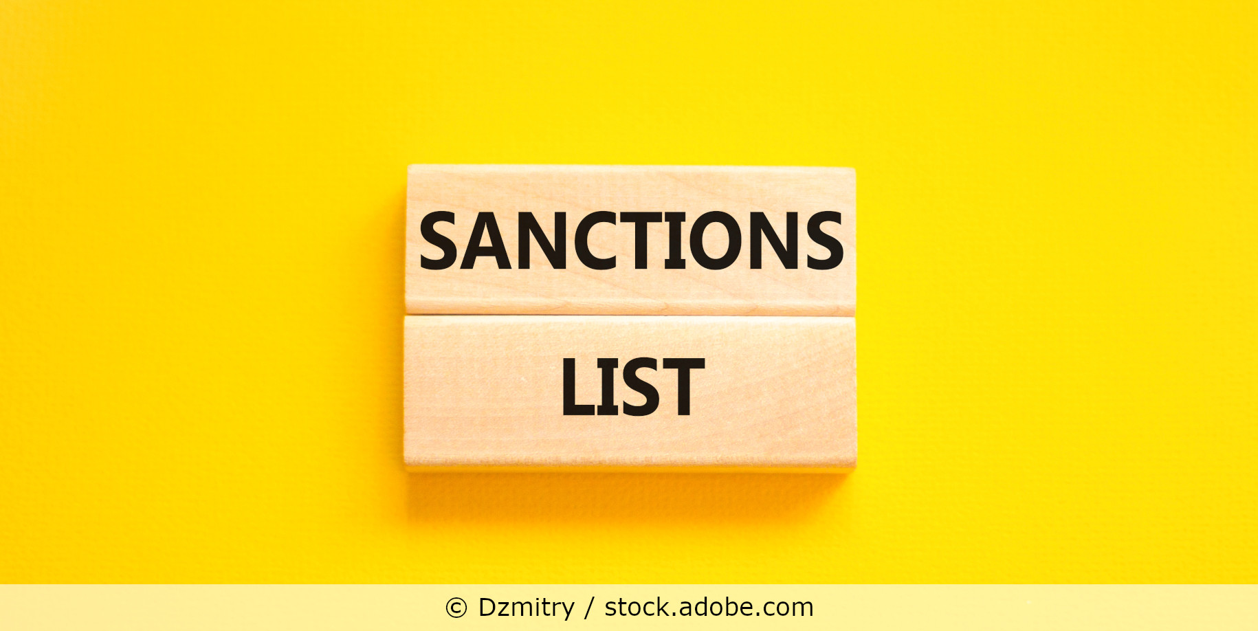 Die Wörter Sanctions List auf zwei Holzklötzchen vor einem gelben Hintergrund.