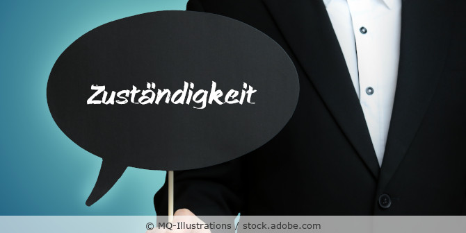 Ein Mann im schwarzen Anzug hält ein Schild in Form einer Sprechblase mit der Aufschrift Zuständigkeit.