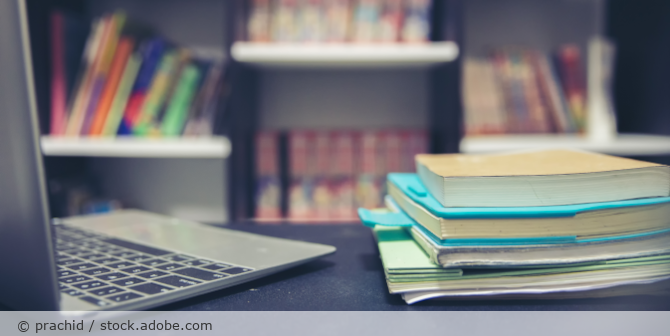 Schreibtisch mit Laptop und Büchern.