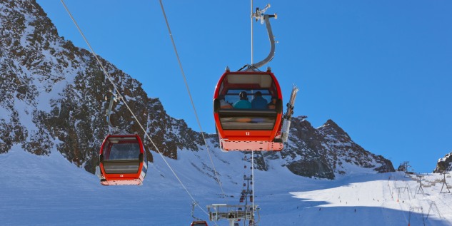 Zwei rote Skigondel die Bergabwärts fahren.