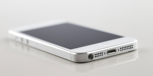 Weißer Smartphone liegt auf einem Weißen Glastisch.