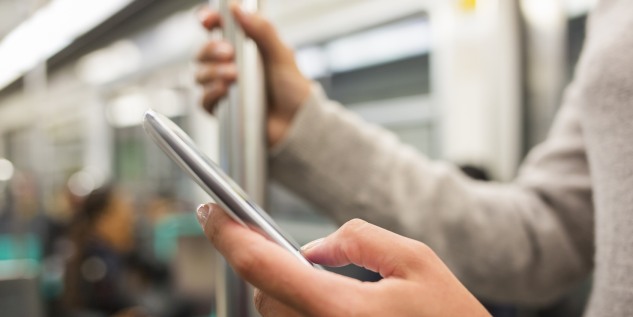 Person in der Bahn und hält den Smartphone in der Hand.