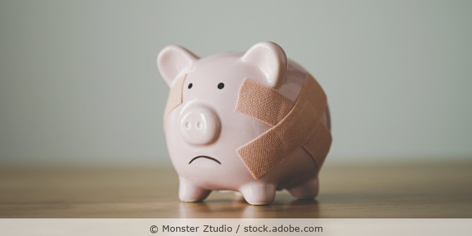 Rosafarbenes Porzellansparschwein mit traurigem Gesicht und Pflaster.