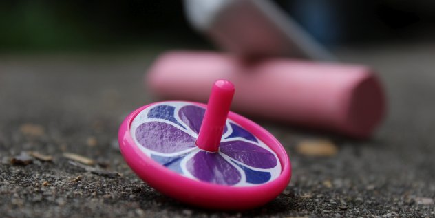 Ein pinkes Spielzeugkreisel liegt auf dem Boden.