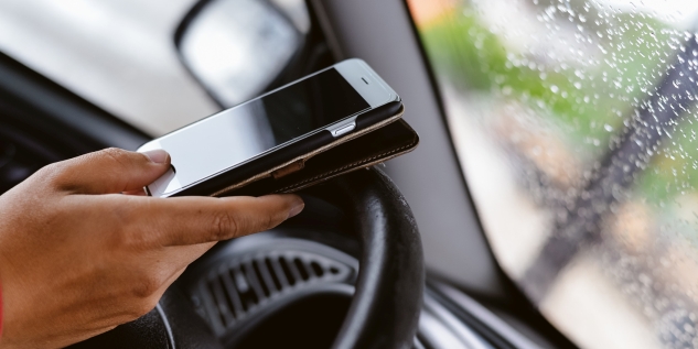 Ein Handy am Steuer von einem Auto.
