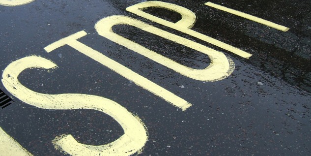 Auf dem Asphalt steht groß das Wort STOP.