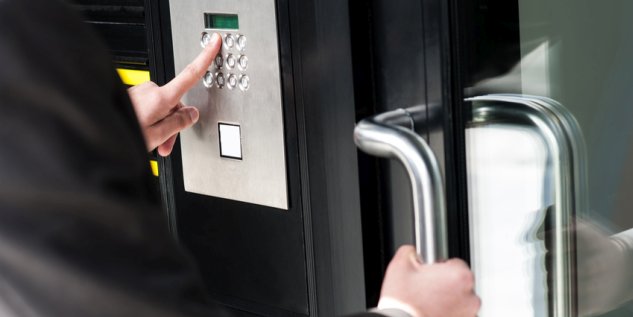 Mann gibt ein Code an der Tür ein um ins Gebäude zu kommen.