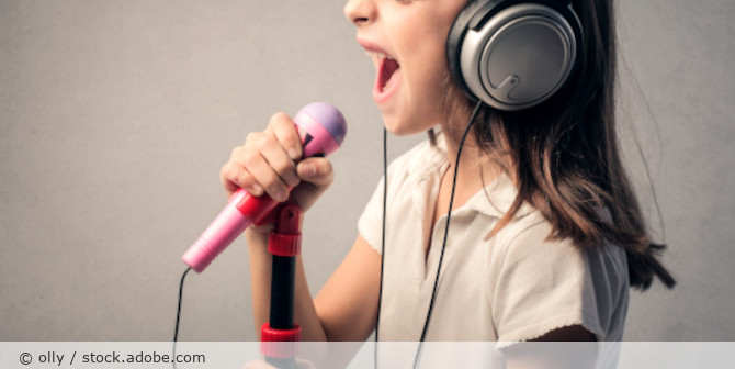 Kind singt in ein Mikrofon.