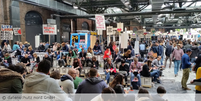 Viele sitzende Menschen bei einer Demonstration mit Plakaten.